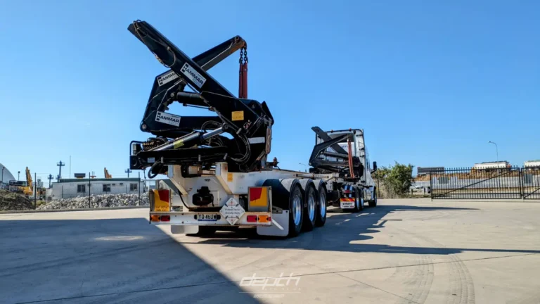 Empty Depth Logistics sideloader trailer with lifting arms raised in a yard