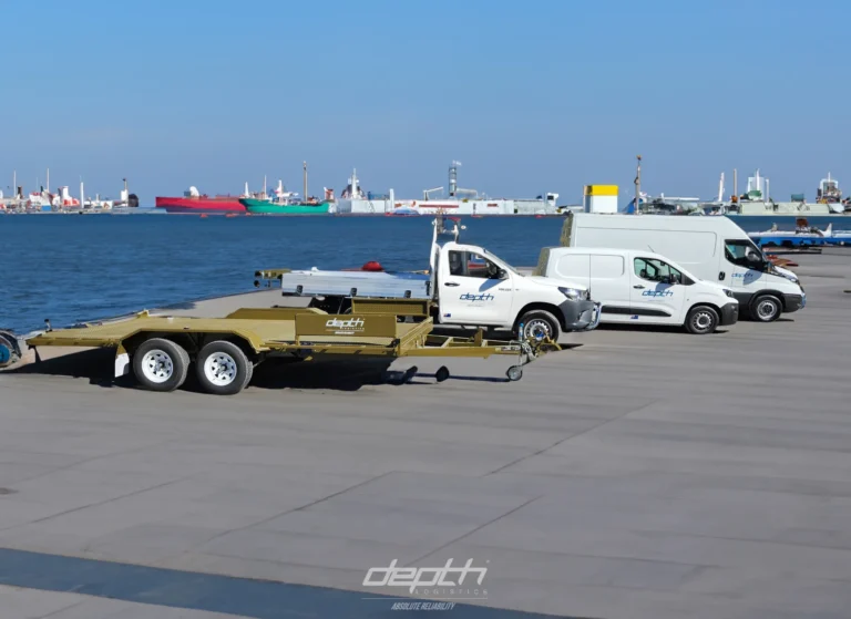 Depth Logistics utes, van and plant trailer parked at a wharf
